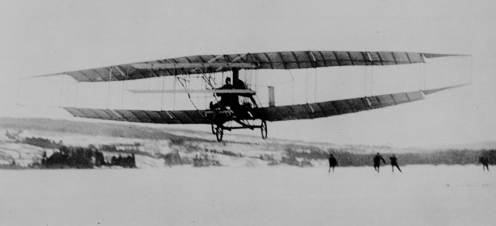 The Silver Dart, carrying John A.D. McCurdy as the aviator, flies over the ice on Baddeck Bay, N.S. On a frozen lake in Cape Breton, Canadian aviation first took flight 111 years ago.