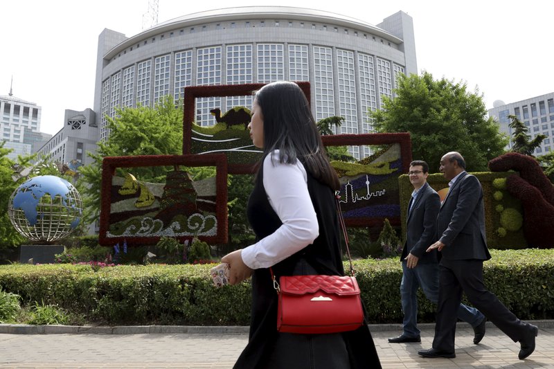 In this April 19, 2019, photo, foreigners pass by the Chinese Foreign Ministry in Beijing, China. China on Wednesday, Feb. 19, 2020 said it has revoked the press credentials of three reporters for the U.S. newspaper Wall Street Journal over a headline for an opinion column deemed by the government to be racist and slanderous. 
