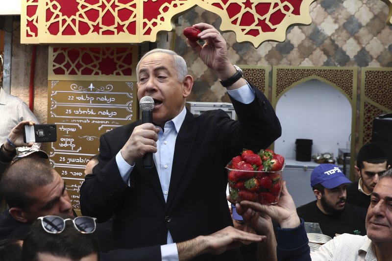 Israeli Prime Minister and head of the Likud party Benjamin Netanyahu holds a strawberry as he speaks during a visit to a market in Jerusalem, Friday, Feb. 28, 2020. 