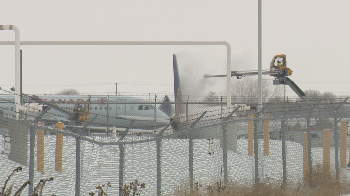 An airport worker de-ices a plane at YYC Calgary International Airport on Saturday, Feb. 8.