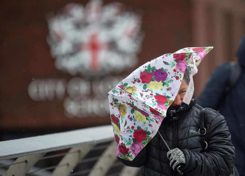 A woman struggles with an umbrella in central London, Saturday, Feb. 15, 2020.