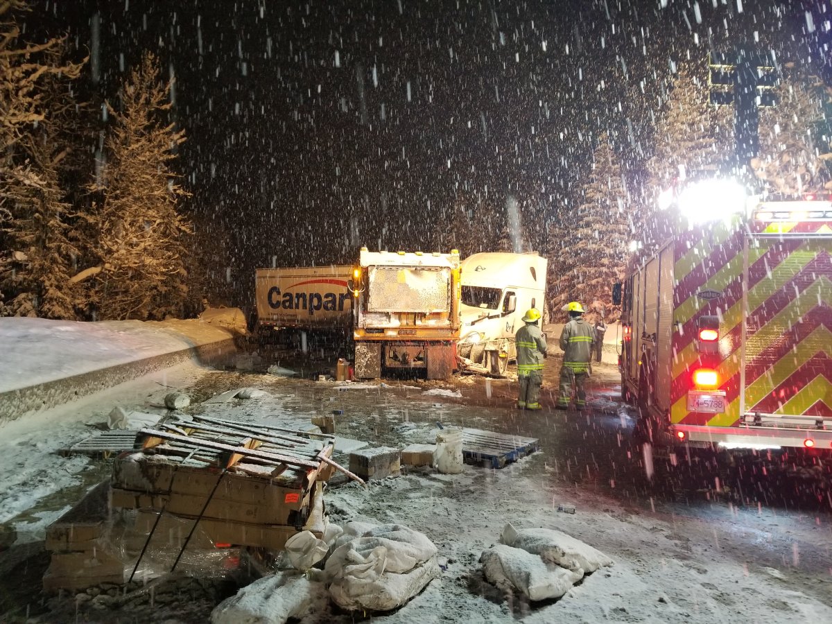 Fire crews at the scene, where a plow truck can be seen facing the jackknifed commercial transport tractor trailer, along with debris scattered across the highway.