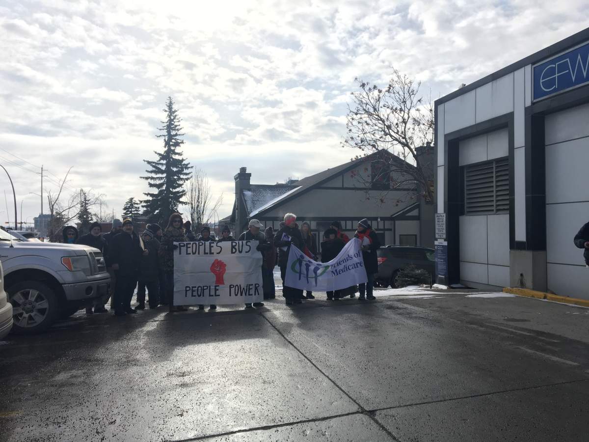 Group walks to Health Minister\’s office with signs.
