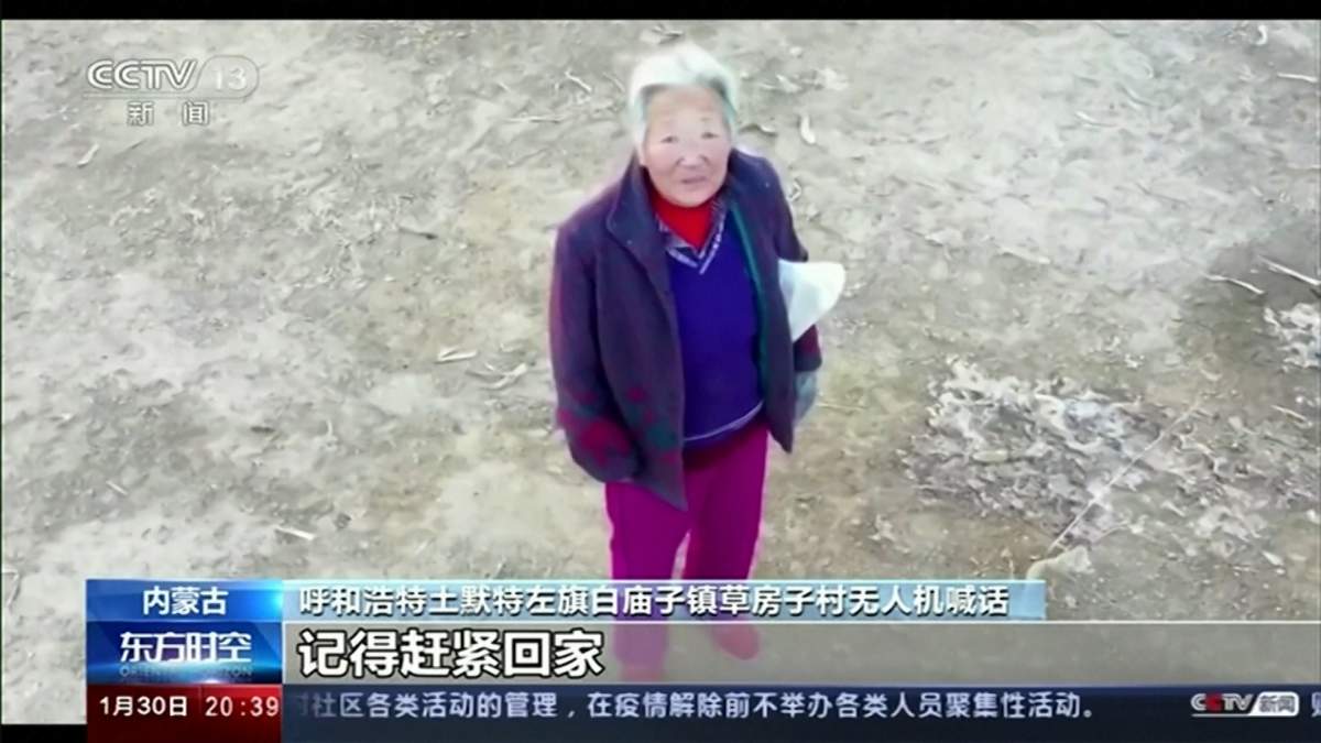 An elderly woman is warned by a police-controlled drone to wear a breathing mask during the coronavirus outbreak in China.
