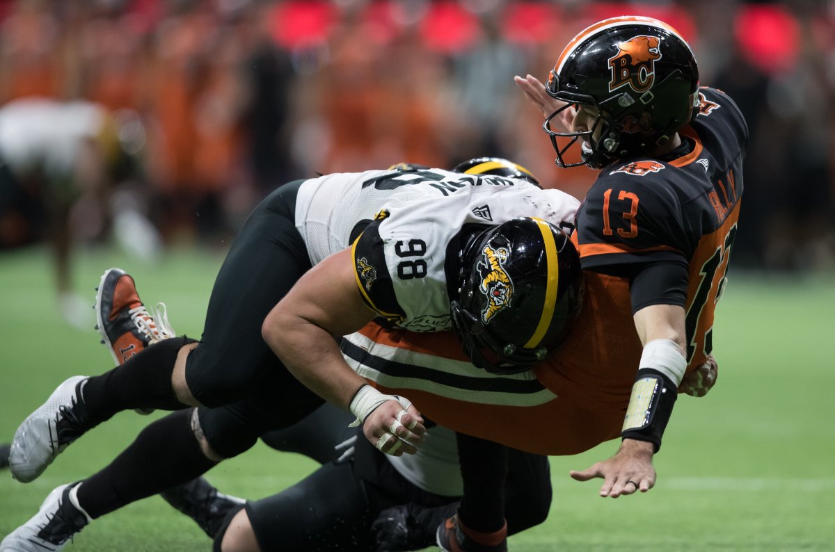 B.C. Lions quarterback Mike Reilly, right, falls to the ground after being hit by Hamilton Tiger-Cats' Dylan Wynn in Vancouver, Saturday, Aug. 24, 2019.