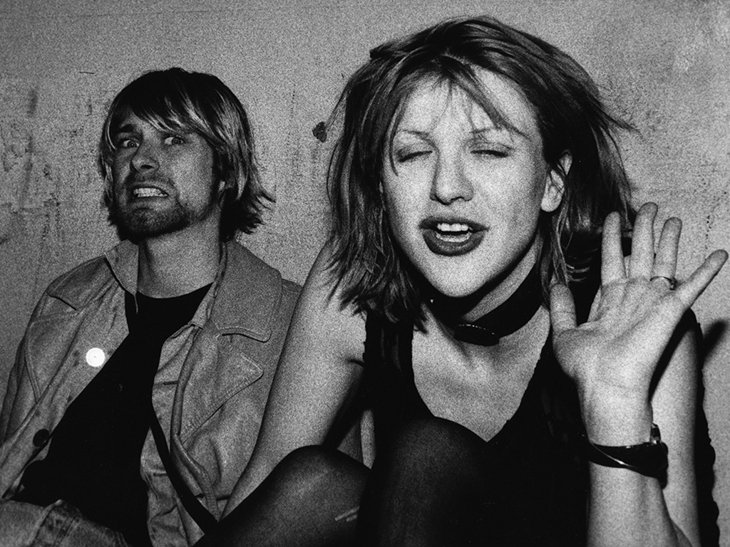 (L-R) Kurt Cobain and Courtney Love pose for photograph, Kurt grimacing for the camera and Courtney waving, on a VIP balcony during Mudhoney concert at the Hollywood Palladium on Dec. 4, 1992 in Los Angeles, Calif.
