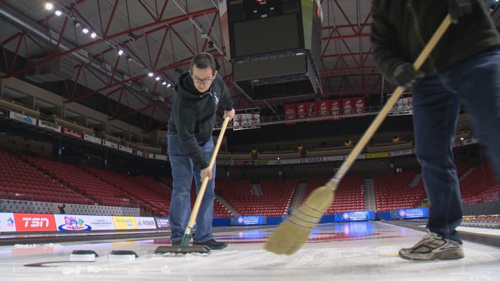 Ice crew members scrape the surface of the ice before pebbling it at Mosaic Place in Moose Jaw.
