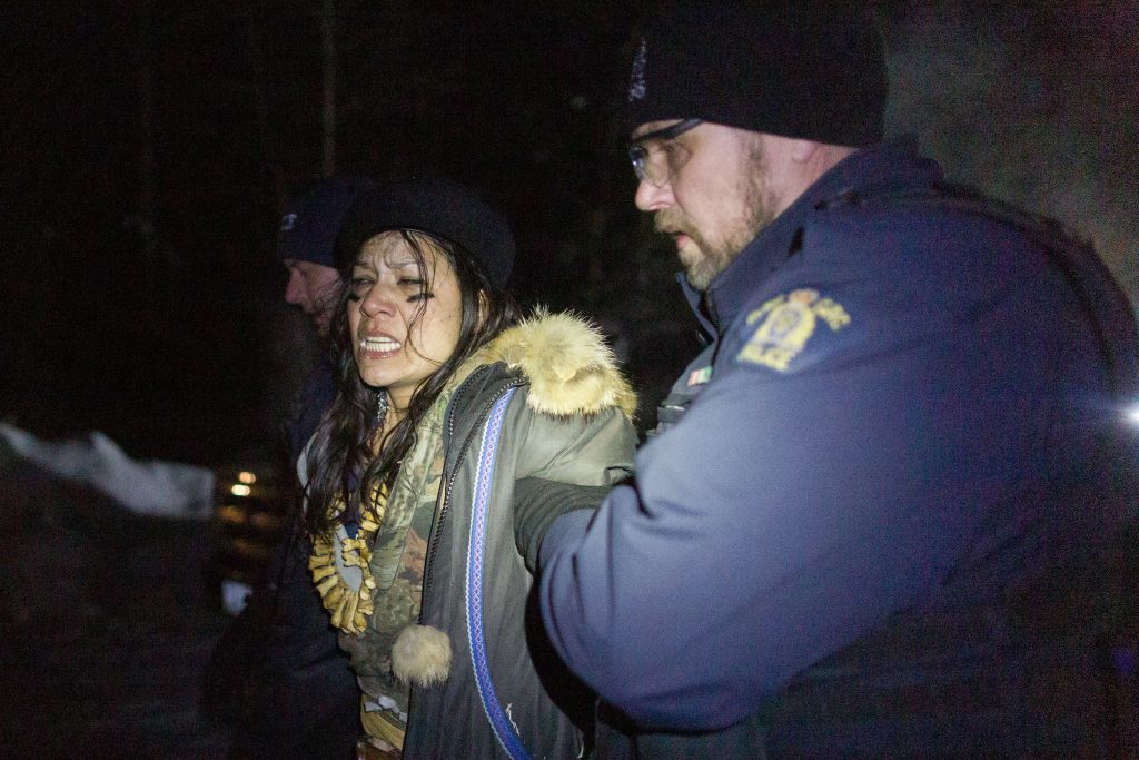 A demonstrator in Wet’suwet’en territory is detained by RCMP officers while they enforce a court injunction on Feb. 6, 2020.
