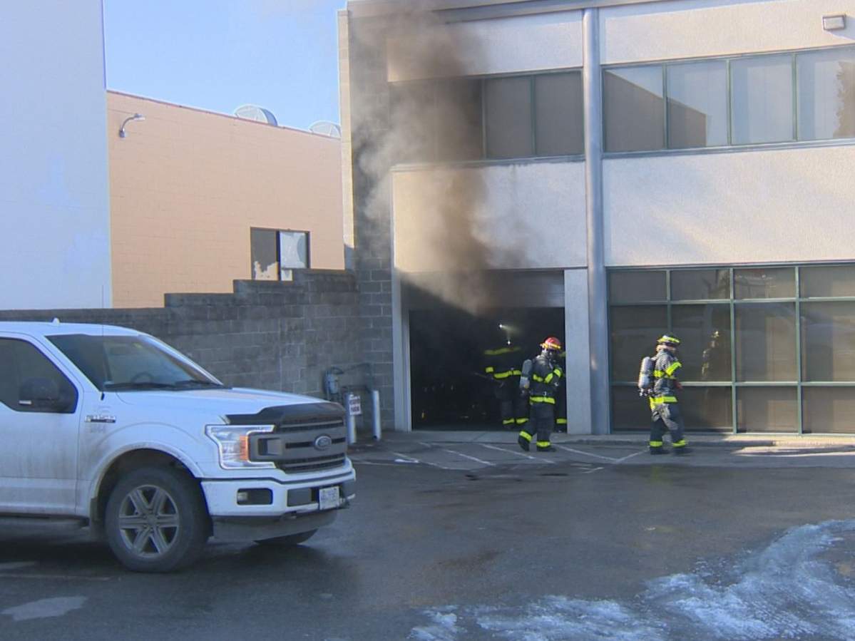 Smoke billow from a business on Moss Court in Kelowna after firefighters opened a bay door.