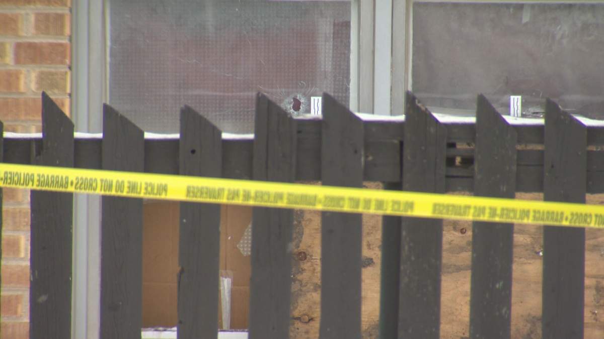 An apparent bullet hole can be seen through a basement window of the apartment building.