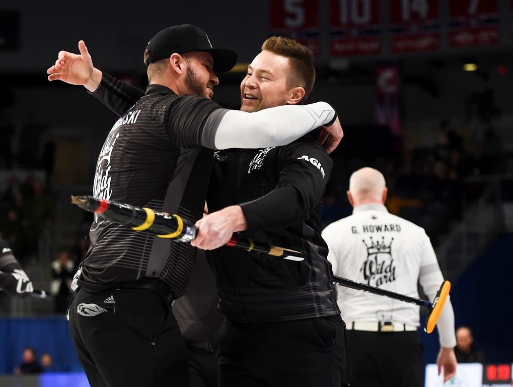 Team McEwen skip Mike McEwen, middle, celebrates his win with second Derek Samagalski as Team Howard skip Glenn Howard, right, walks off following the wild card game at the Brier in Kingston, Ont., on Friday, Feb. 28, 2020.