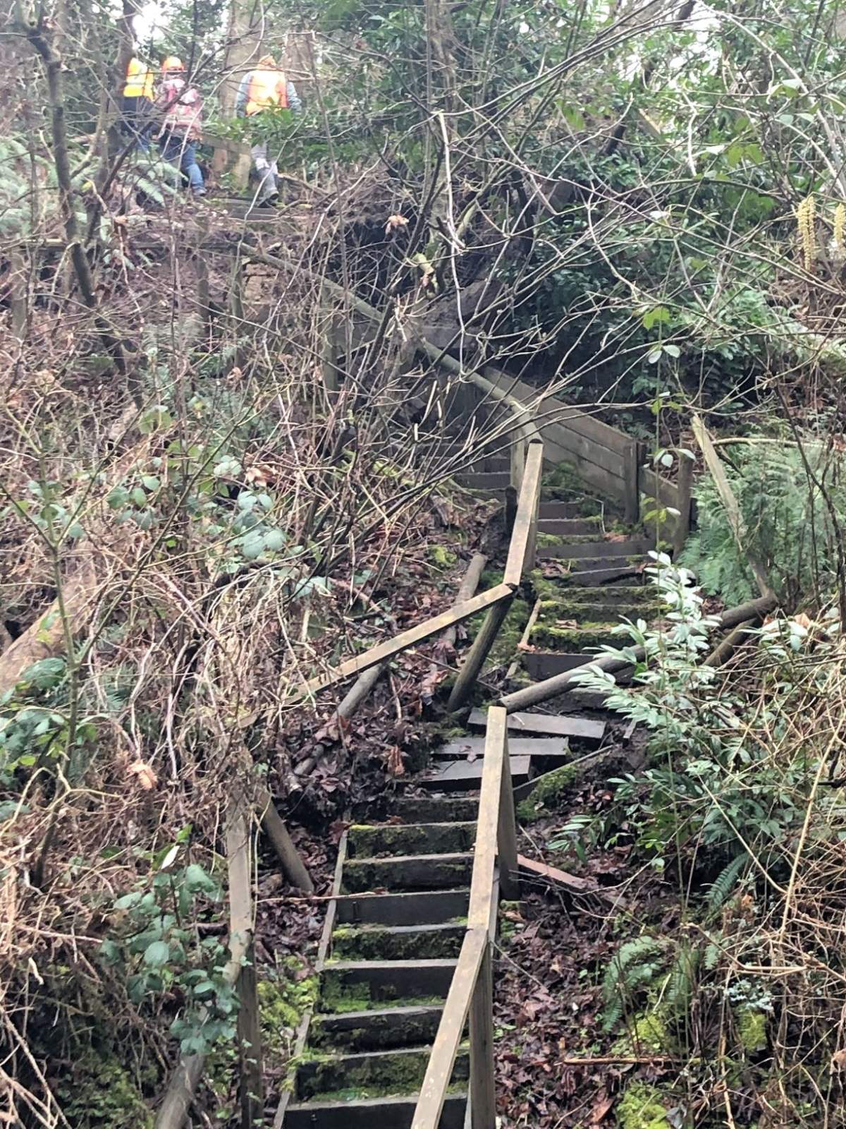 Workers look at the damage to stairs in the east part of Ruth Johnson Park.