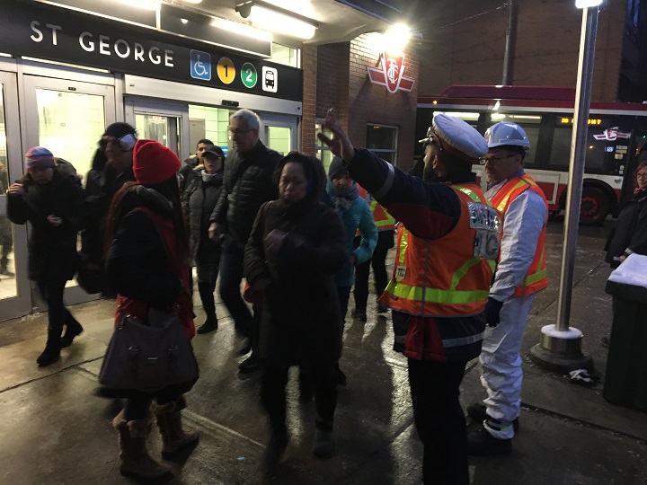 A TTC worker is directing commuters after a portion of Line 1 was shut down Thursday morning, forcing riders onto shuttle buses.