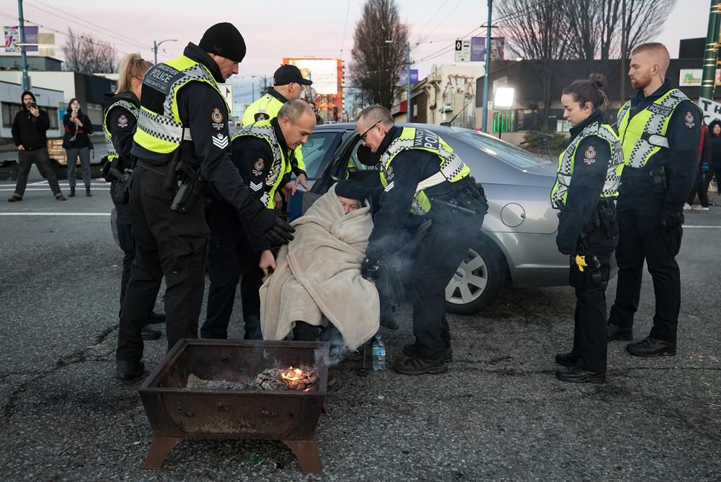 Police officers remove an elderly woman from the road where protesters demonstrating in solidarity with Wet'suwet'en hereditary chiefs opposed to construction of the Coastal GasLink natural gas pipeline across their traditional territories were blocking an entrance to the port, in Vancouver, on Monday February 10, 2020.