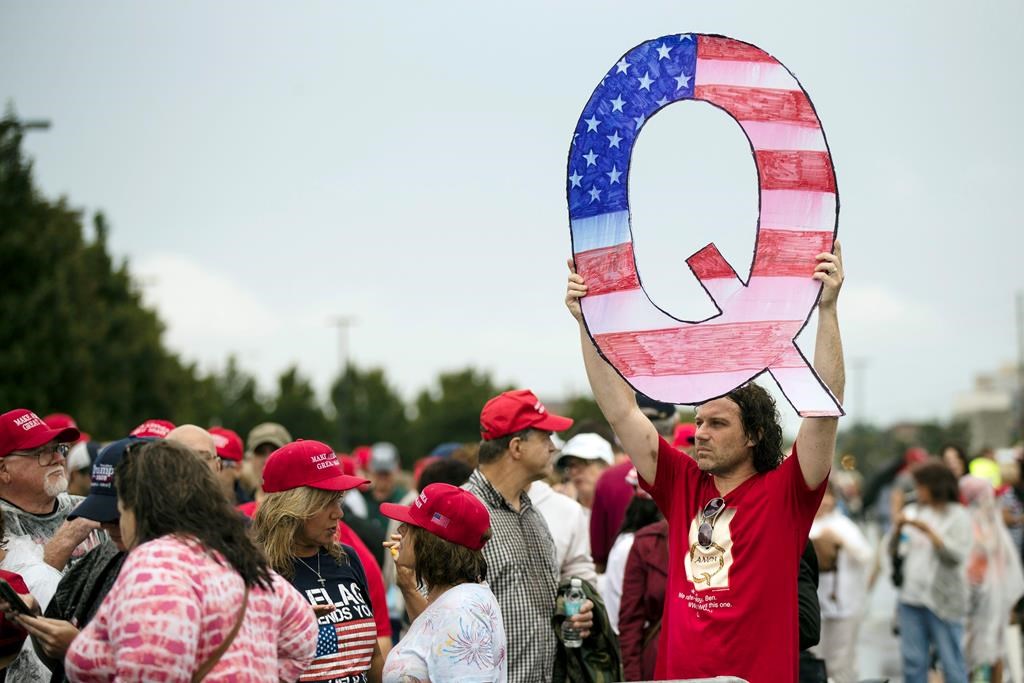 FILE - In this Aug. 2, 2018, file photo, David Reinert holding a Q sign waits in line with others to enter a campaign rally with President Donald Trump in Wilkes-Barre, Pa. A far-right conspiracy theory forged in a dark corner of the internet is creeping into the mainstream political arena. It's called QAnon, and it centers on the baseless belief that President Donald Trump is waging a secret campaign against enemies in the “deep state.” (AP Photo/Matt Rourke, File).