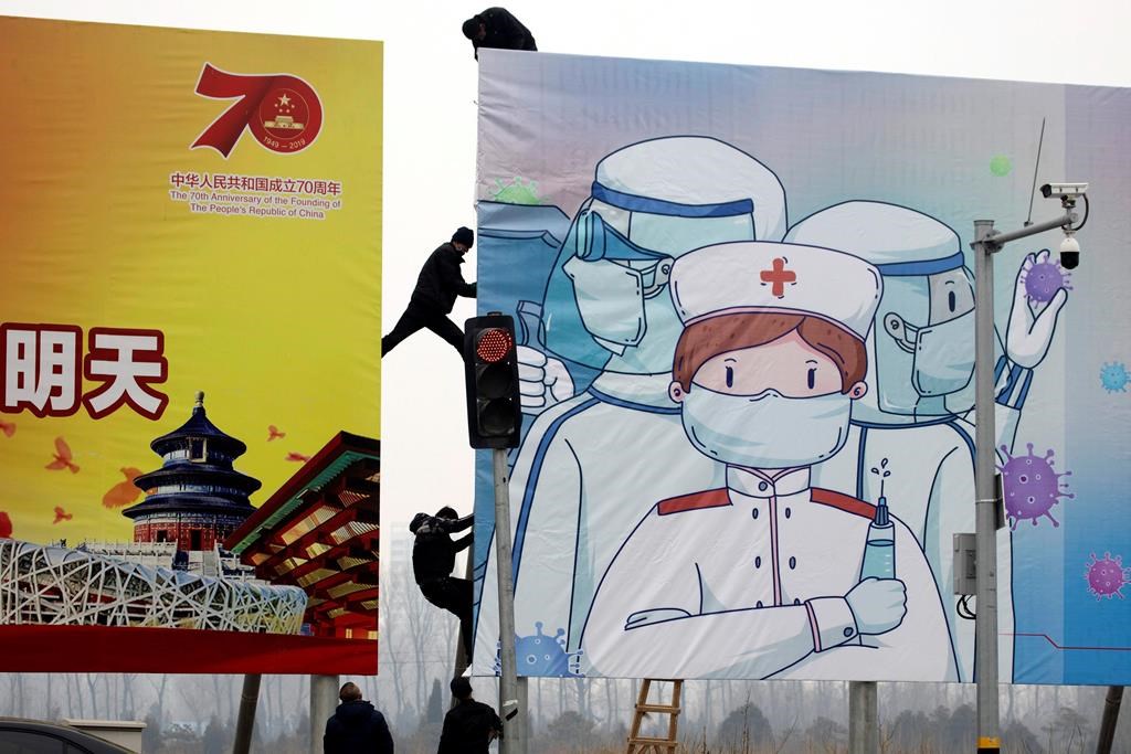 Workers put up government propaganda to fight against the viral outbreak in Beijing, China on Thursday, Feb. 20, 2020. A viral outbreak that began in China has infected more than 75,000 people globally. The World Health Organization has named the illness COVID-19, referring to its origin late last year and the coronavirus that causes it.