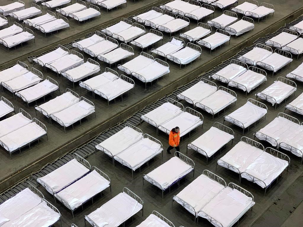 Workers arrange beds in a convention center that has been converted into a temporary hospital in Wuhan in central China's Hubei Province, Tuesday, Feb. 4, 2020.