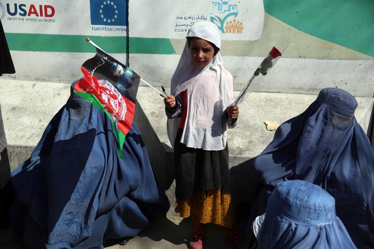 A young girl holds a rose during an event marking the International Women’s Day in Kabul, Afghanistan, Sunday, March 8, 2020. (AP Photo/Rahmat Gul)