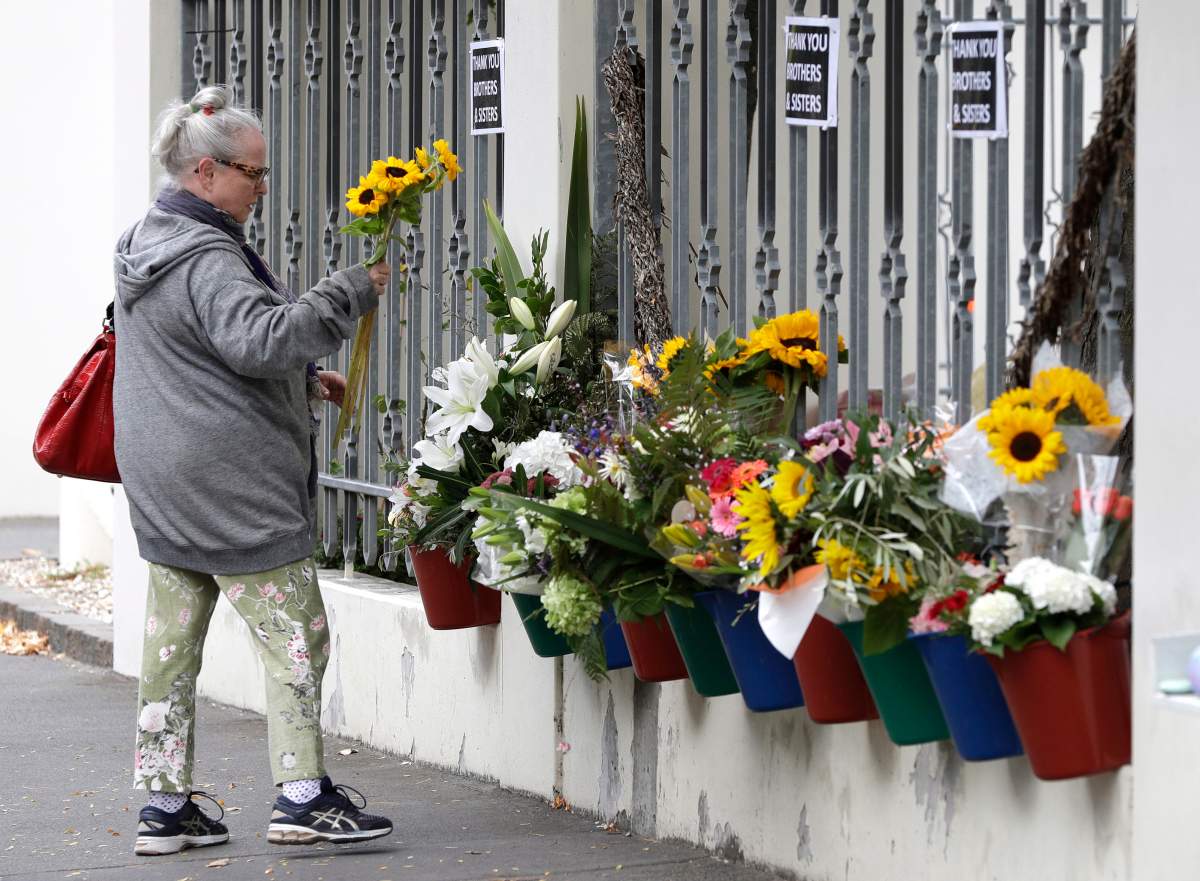 A woman prepares to lay flowers outside the Al Noor mosque in Christchurch, New Zealand, Sunday, March 15, 2020.