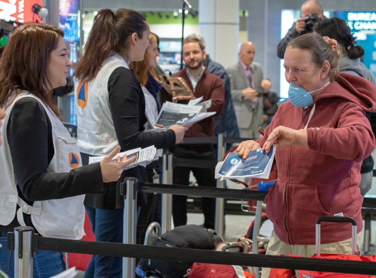 Quebec health-care workers assigned by the City of Montreal hand out information pamphlets on COVID-19 procedures to passengers arriving from abroad at Trudeau International Airport on Monday, March 16, 2020 in Montreal.