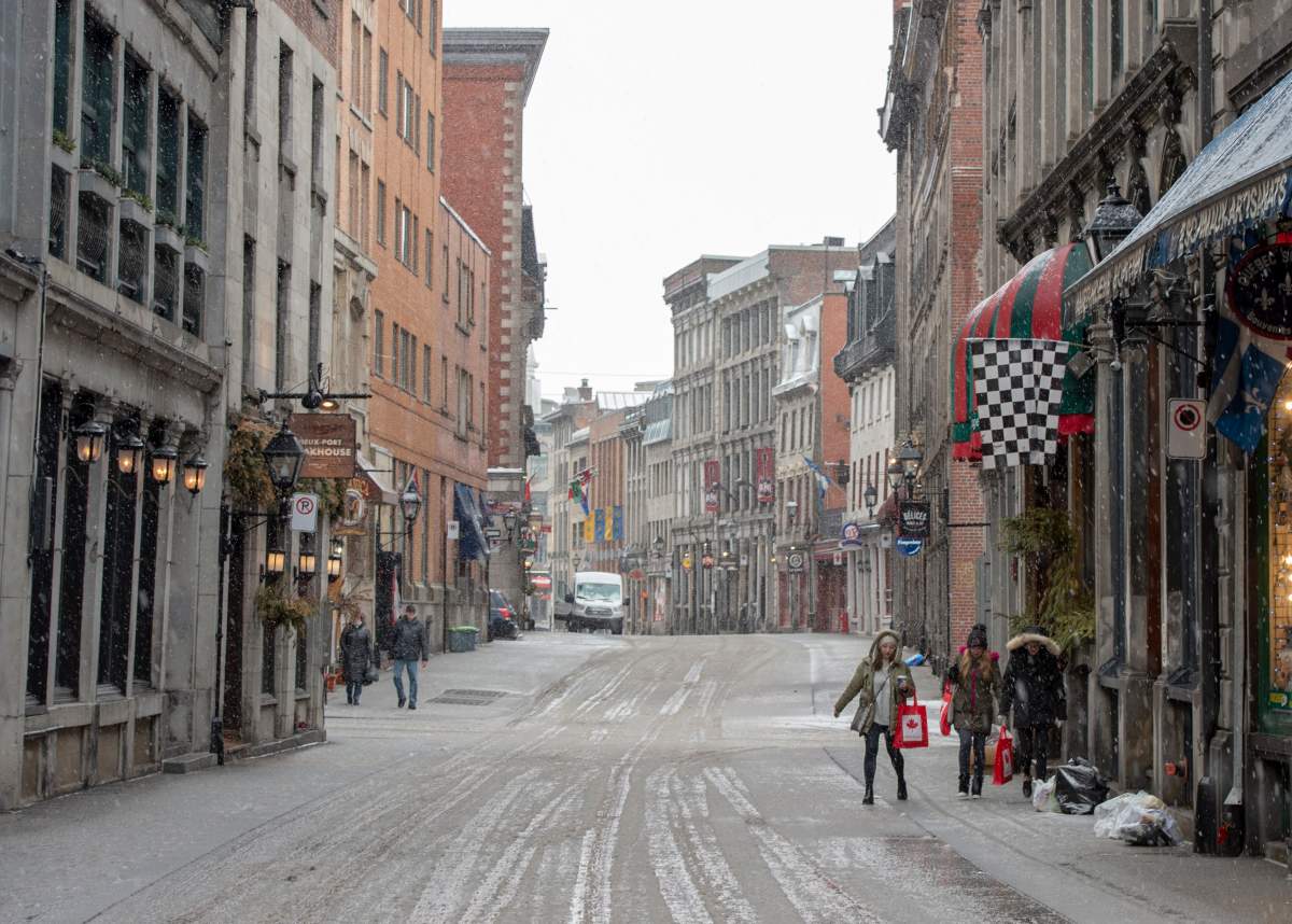 Tourists walk along the street as Old Montreal is nearly deserted, Tuesday, March 17, 2020 in Montreal. Quebec premier promises aid for hotels feeling impact of pandemic on tourism.