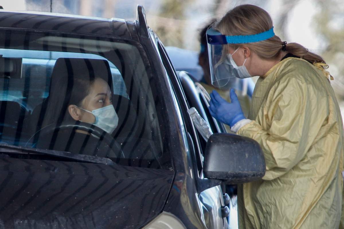 Alberta Health Services employees speak with a drivers at a drive-thru testing facility in Calgary, Alta., Friday, March 27, 2020, amid a worldwide COVID-19 pandemic.