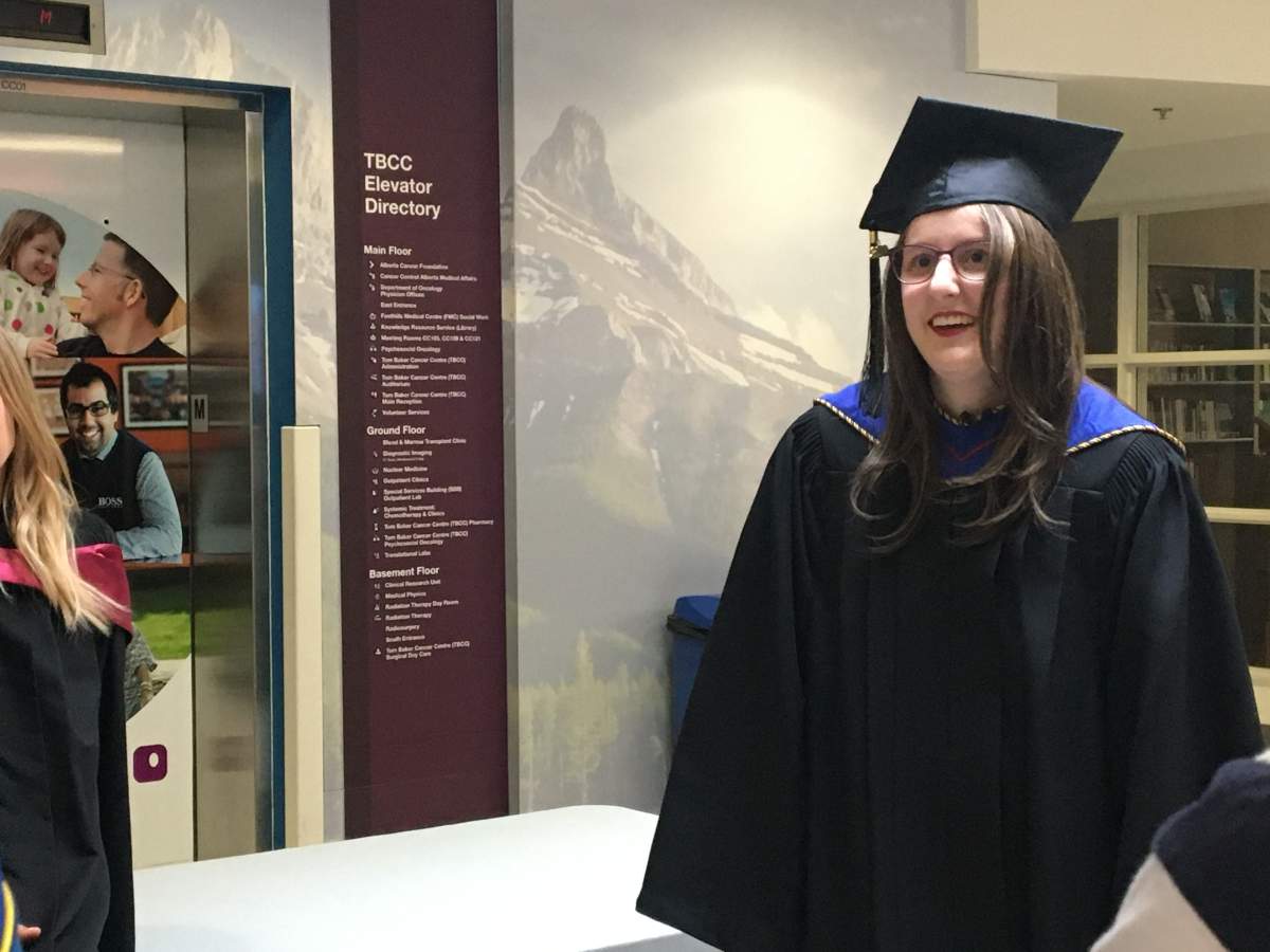 Alysha in her graduation gown outside Tom Baker auditorium.
