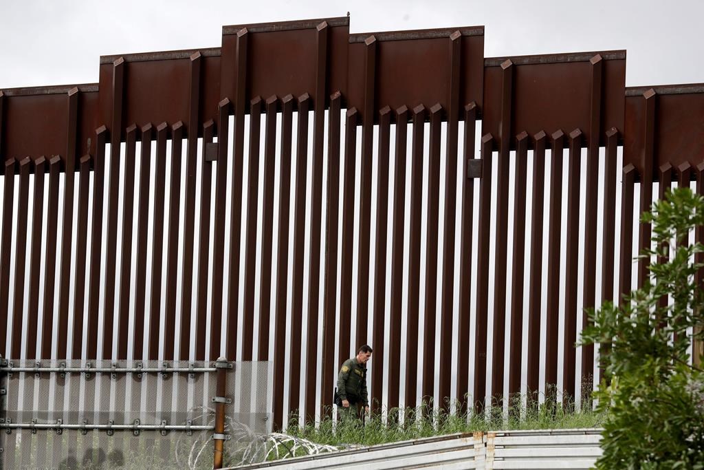 A border patrol agent walks along a border wall separating Tijuana, Mexico, from San Diego, Wednesday, March 18, 2020, in San Diego.