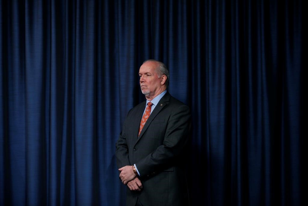 Premier John Horgan listens to questions over the phone from media as he joins Minister Mike Farnsworth to provide government measures in regards to the COVID-19 pandemic during a press conference in the press gallery at Legislature in Victoria, B.C., on Thursday March 26, 2020. THE CANADIAN PRESS/Chad Hipolito.