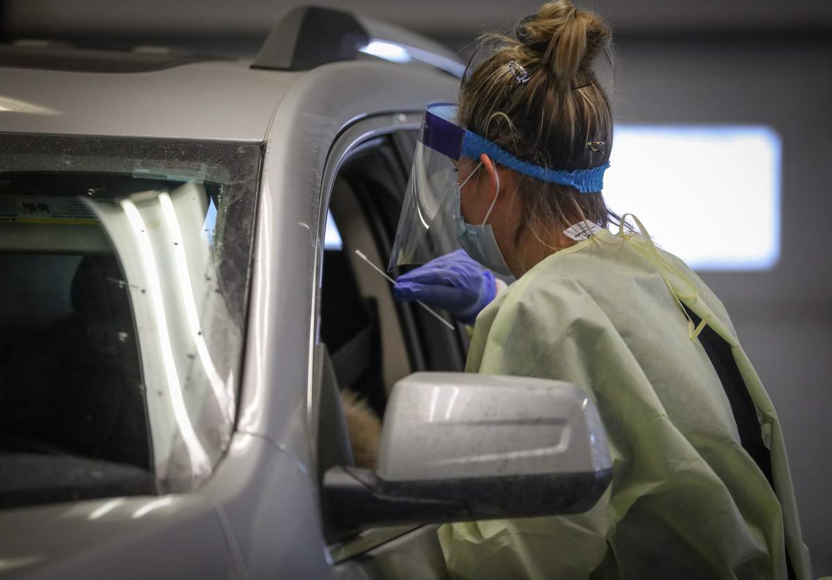 An AHS worker administers a swab test for COVID-19 at a drive-thru testing centre in Calgary. 