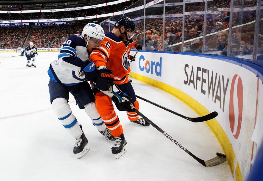 The Winnipeg Jets’ Andrew Copp (9) and the Edmonton Oilers’ Adam Larsson (6) battle for the puck during third-period NHL action in Edmonton, Saturday, Feb. 29, 2020. THE CANADIAN PRESS/Jason Franson
