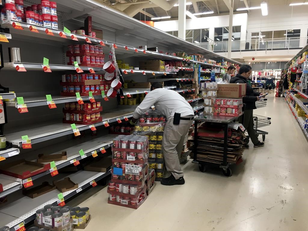 Workers restock grocery store shelves with canned goods early in the morning in Toronto on Friday March 13, 2020.