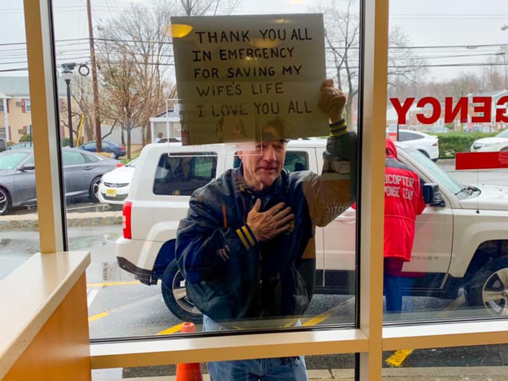 A mystery man held up a sign at a New Jersey hospital, thanking emergency room workers for saving his wife's life.