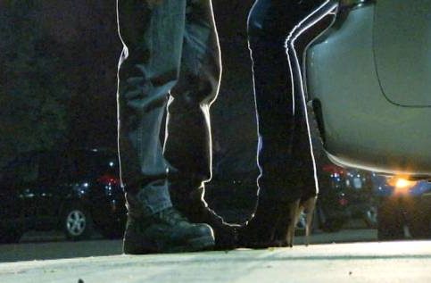 File: Two people standing in front of a car at night.