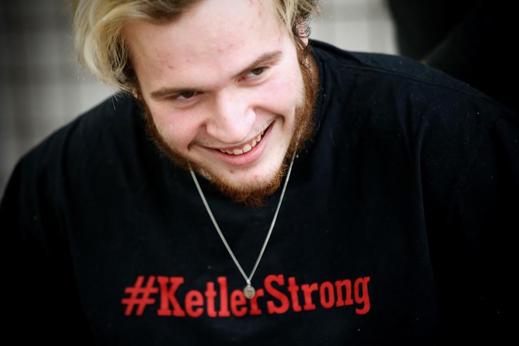 Reese Ketler, a 19-year-old who was paralyzed during a hockey game in December, wears a necklace with his jersey number and a t-shirt with his hashtag as works through his rehabilitation with physiotherapist Kevin Stewart at the Health Sciences Centre in Winnipeg, Thursday, March 5, 2020.