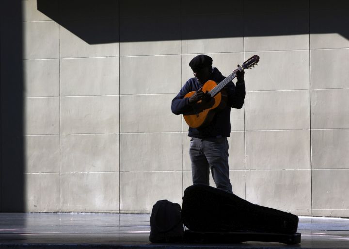 A lone street performer tunes his guitar on the deserted Hollywood Boulevard in Los Angeles on Tuesday, March 24, 2020. 