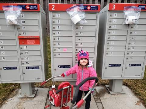 Lily Chesterfield, 3, helped to secure packages of toilet paper to community mailboxes for those in need in the Oakridge area of London, Ont.