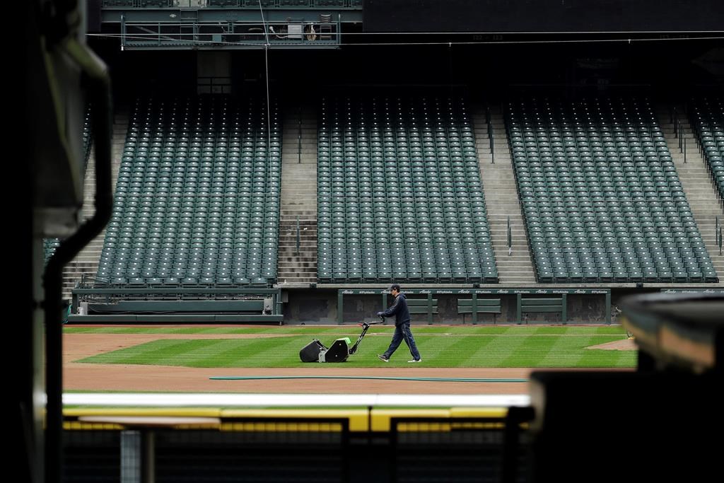 A grounds crew worker cuts the infield in front of empty seats at T-Mobile Park in Seattle, March 26, 2020, around the time when the first pitch would have been thrown in the Mariners' Opening Day baseball game against the visiting Texas Rangers.