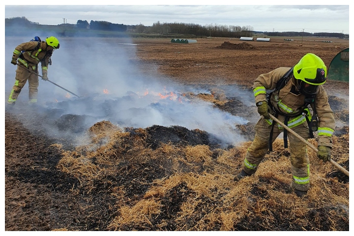 Firefighters rake up the hay in a pigpen to stop a fire north of Leeds, U.K., on March 7, 2020.