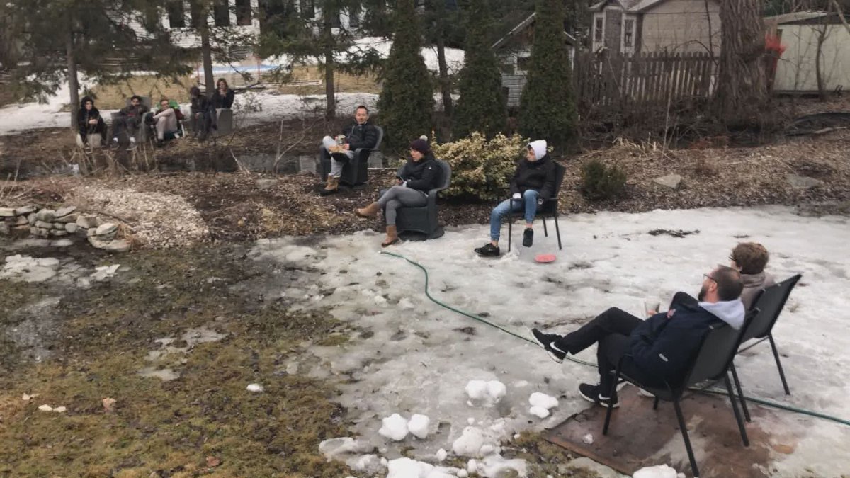 A backyard cocktail party on in Pointe-Claire with three neighbours on two yards practicing social distancing. It’s their way of getting together while being safe. Monday March 30, 2020.