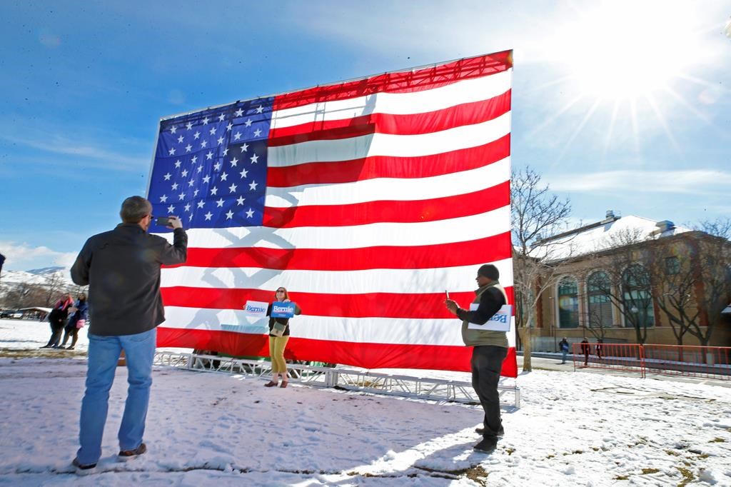 Supporters of Democratic presidential candidate Bernie Sanders take pictures in front of a large American flag before a rally Monday, March 2, 2020, in Salt Lake City. Sanders is making a stop in Salt Lake a day before Super Tuesday primaries, which Utah is a part of.