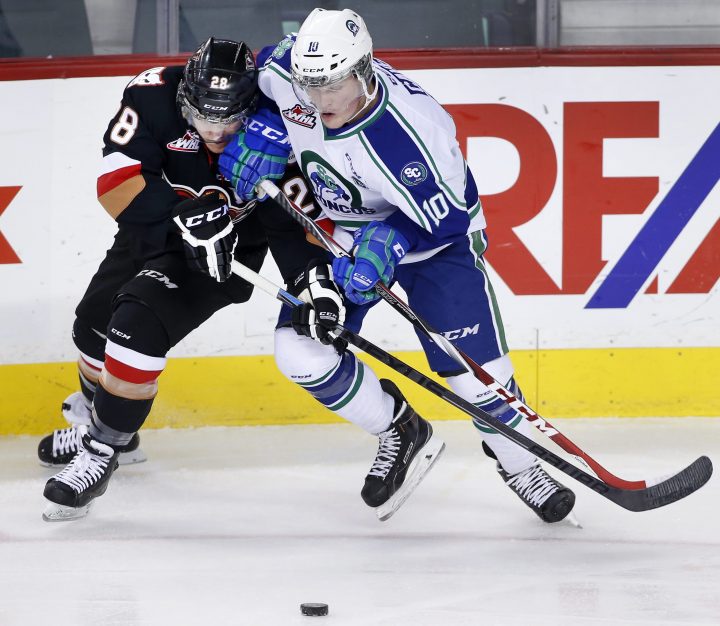 Swift Current Broncos’ Colby Cave, right, battles for the puck with Calgary Hitmen’s Elliott Peterson during WHL hockey action in Calgary on Nov.28, 2014.