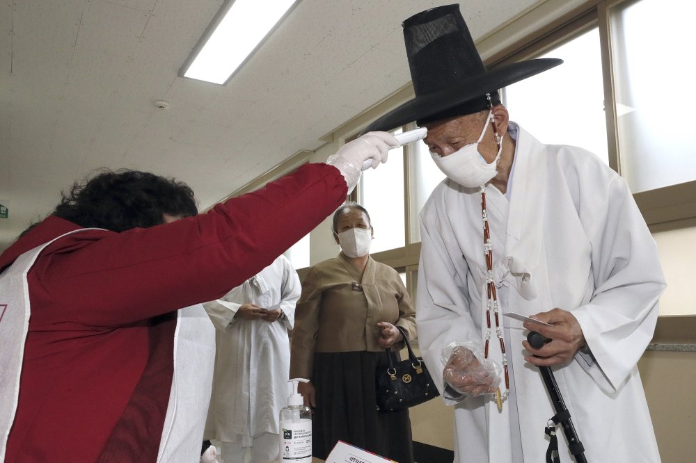 A South Korean Confucian scholar wearing a face mask to help protect against the spread of the new coronavirus has his temperature checked upon his arrival to cast his vote for the parliamentary elections at a polling station in Nonsan, South Korea, Wednesday, April 15, 2020. South Korean voters wore masks and moved slowly between lines of tape at polling stations on Wednesday to elect lawmakers in the shadows of the spreading coronavirus. 