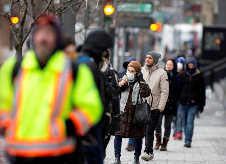 A woman adjusts her mask while she waits in line as the city's public health unit holds a walk-in clinic testing for coronavirus disease (COVID-19) in Montreal, March 23, 2020.