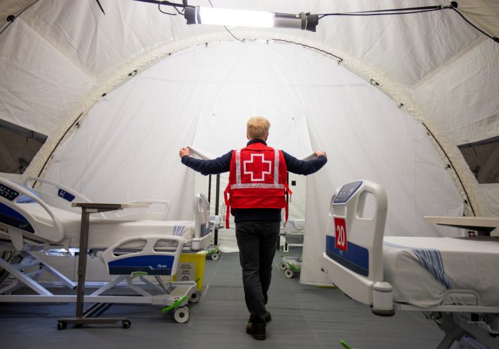A volunteer with the Red Cross shows a doorway between beds in a mobile hospital set up in partnership with the Canadian Red Cross in the Jacques-Lemaire Arena in Montreal, Que., April 26, 2020.