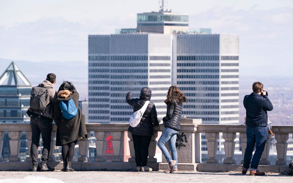 People they look over the city of Montreal from Mount Royal Park on Friday, March 27, 2020.
