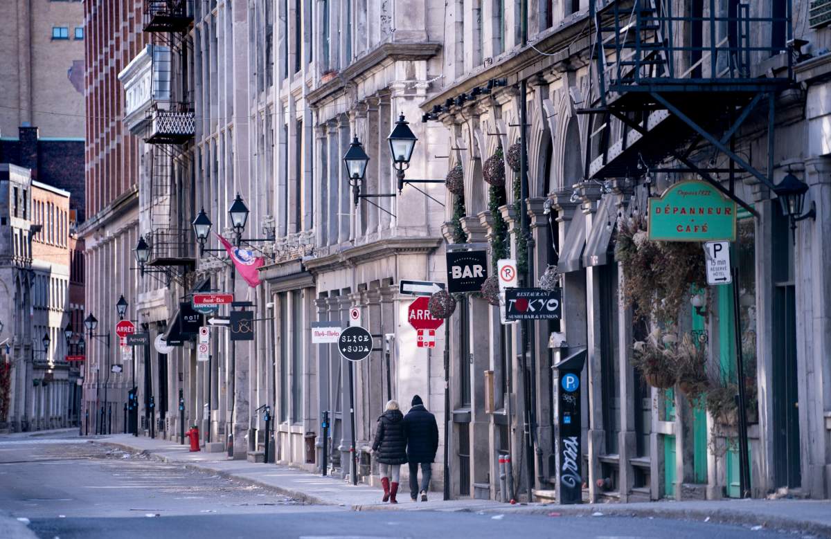 A couple walks along a deserted street in Old Montreal on Tuesday, March 31, 2020. 