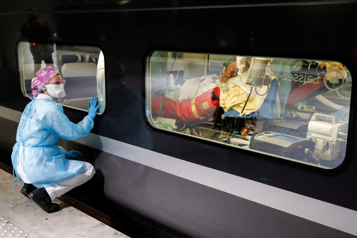 A member of the medical staff watches from the platform as a patient infected with the COVID-19 virus is lays in a train at the Gare d’Austerlitz train station, Paris, April 1, 2020.