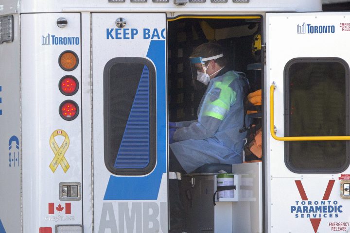 A paramedic sits in the back of an ambulance as a patient is brought into a Toronto hospital, on Wednesday, April 1, 2020.