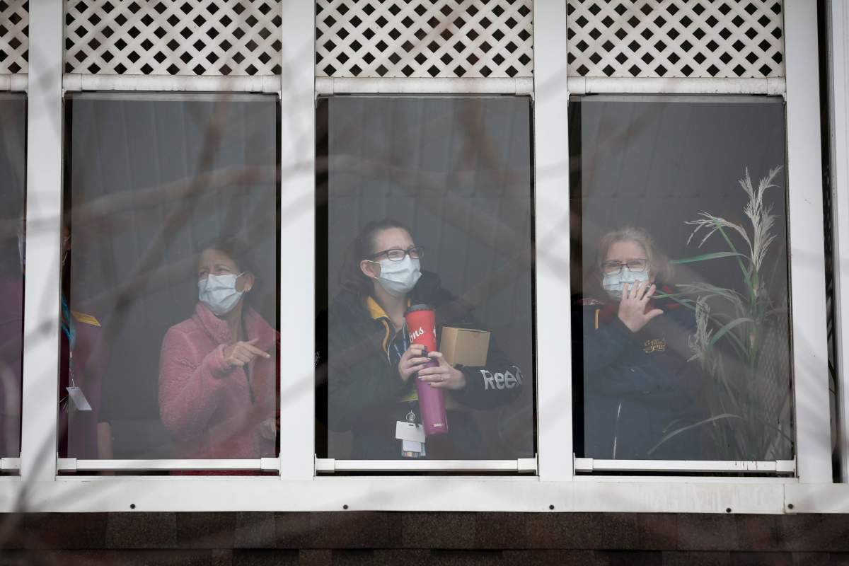 Staff members wave to family and friends who came out to show support for residents and staff in Calgary's McKenzie Towne Long Term Care Centre, where there have been dozens of confirmed COVID-19 cases, on Thursday, April 2, 2020.